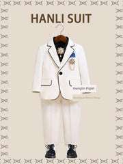 A white children's suit with black trim, a black shirt, and decorative brooches.
