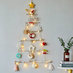 A DIY wooden ladder Christmas tree wall hanging decorated with ornaments and string lights.