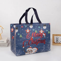 A blue non-woven Christmas gift bag featuring a Santa Claus and snowman pattern with Merry Christmas text.