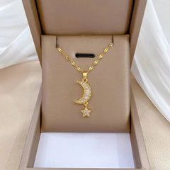 A gold-toned stainless steel necklace featuring a crescent moon and star pendant with clear stones.