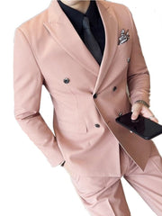 A man wears a slim-fit, double-breasted pink suit with a black shirt and dark tie.