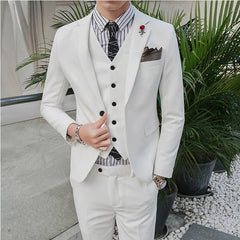 A man wears a slim-fit white three-piece suit with a striped shirt and a patterned tie.