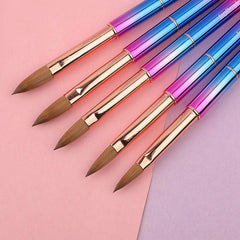 Five professional Kolinsky acrylic nail brushes with colorful metallic handles on a pink background.