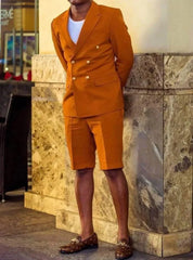 A man wears a brown double-breasted suit jacket with matching shorts and patterned loafers.