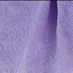 A close-up view of light purple fabric featuring an intricate, tone-on-tone floral jacquard pattern.