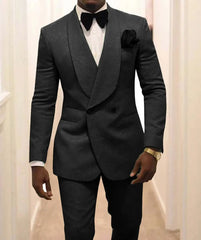 A man wears a dark patterned two-piece tuxedo with a shawl lapel, white shirt, and black bow tie.