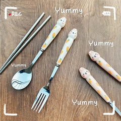 A set of stainless steel cutlery featuring white handles decorated with cartoon rabbits and carrots.