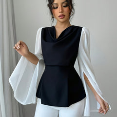 A woman wears an elegant black top with a draped neckline and long, split white sleeves.