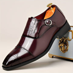 A burgundy men's monk strap dress shoe with a unique embossed pattern and a black sole.