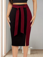 A slim-fit black and burgundy color-block midi skirt featuring an adjustable ribbon bow waist.