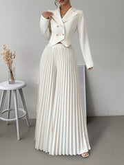 A woman wears a white long-sleeved double-breasted blazer paired with matching pleated wide pants.