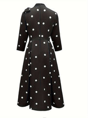 A black fit and flare dress with white polka dots, a high neck, and three-quarter sleeves.