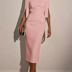 A woman wears a light pink knee-length pencil dress with split sleeves detailed with pearls.