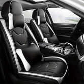 Black and white faux leather car seat covers with matching headrest and lumbar pillows.