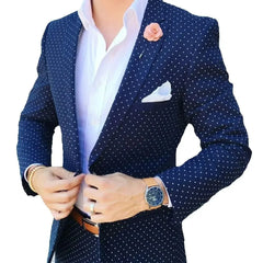 A man wears a dark blue slim-fit blazer with white polka dots, a peaked lapel, and a pink lapel pin.