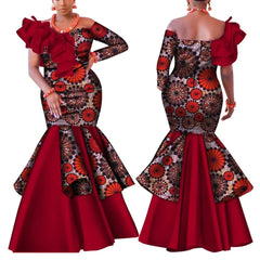 A woman models a red and patterned African-style mermaid dress with a one-shoulder ruffled neckline.