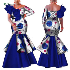A woman models a one-shoulder, ankle-length African dress with a blue and white patterned bodice.