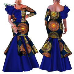 A woman models a blue and orange patterned African-style dress with a one-shoulder ruffled design.