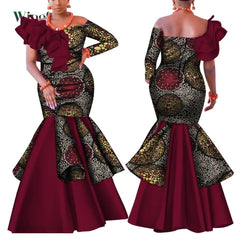 A woman models a long, one-shoulder African print dress with a ruffled bodice and flared skirt.