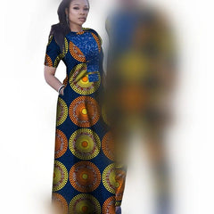 A woman wears a blue floor-length dress featuring a vibrant orange and yellow circular pattern.