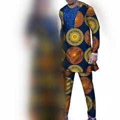A man wears a long-sleeved tunic and matching trousers featuring a vibrant circular African print.