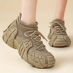 A pair of beige, lace-up casual sneakers with a unique textured sole and breathable fabric upper.