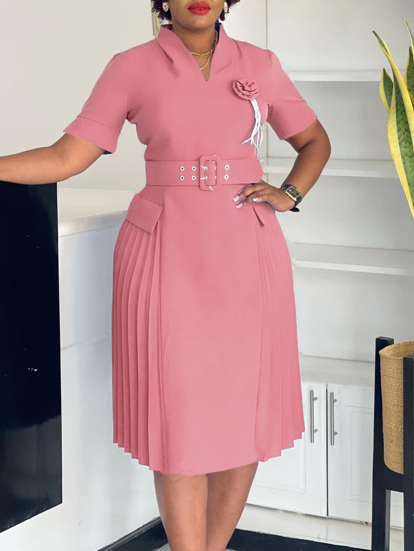 A dusty pink V-neck dress with short sleeves, a matching belt, and a pleated skirt.