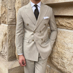 A slim-fit, double-breasted beige suit with subtle stripes and a peak lapel.