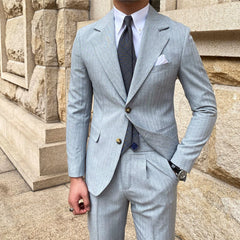 A man wears a light blue striped slim-fit suit with a wide lapel and a dark patterned tie.