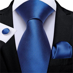 A navy blue silk necktie set featuring a subtle grid pattern with a matching pocket square and cufflink.