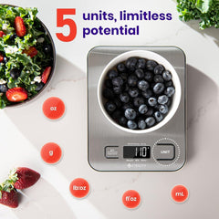 A stainless steel digital kitchen scale with a bowl of blueberries on a white marble surface.