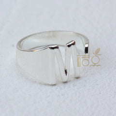 A silver-plated open ring featuring a prominent letter M design.