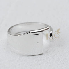 A silver-plated open ring with a flat, rectangular front panel on a plain band.