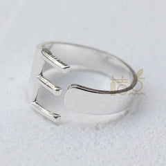 A silver-plated open ring shaped like the letter E on a white background.
