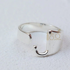 A silver-plated open ring shaped like the letter J on a white background.