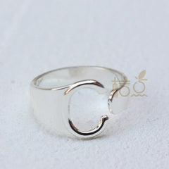 A silver-plated open ring shaped like the letter C resting on a white surface.
