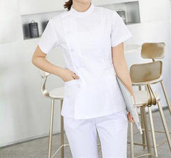 A person wearing a white short-sleeved medical scrub top with a side-button closure and matching pants.