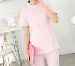 A person wearing a light pink short-sleeved medical scrub top and matching pants.