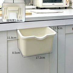 A beige plastic hanging trash can mounted on a cabinet door with dimensions labeled in centimeters.