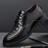 A black lace-up dress shoe with a pointed toe and a textured crocodile-patterned finish.