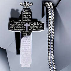 A stainless steel cross pendant necklace engraved with the Lord's Prayer on a silver chain.