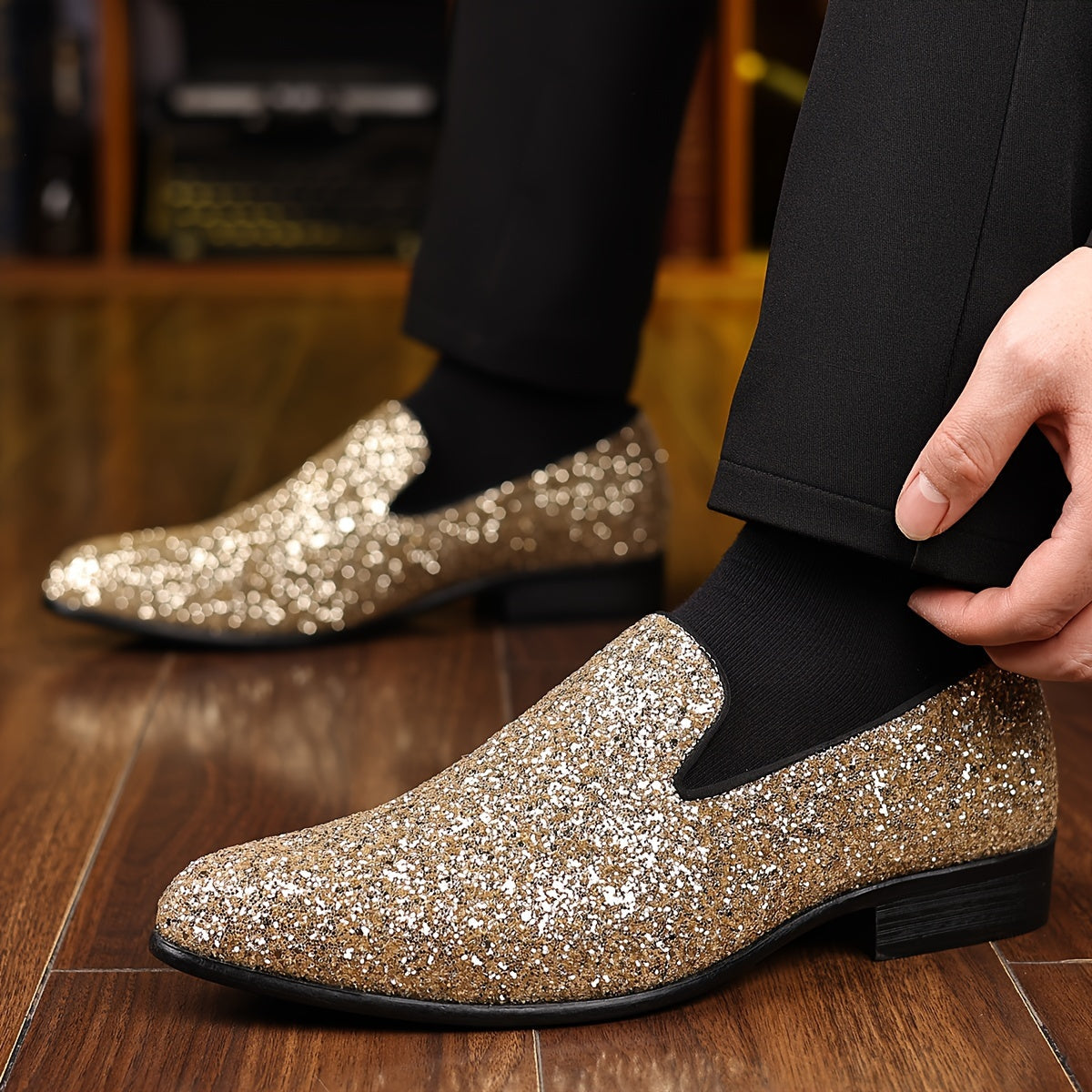 A pair of men's gold glitter slip-on dress shoes with a pointed toe and black rubber sole.
