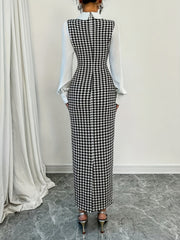 A woman wears a black and white houndstooth bodycon dress with a white collar and long sleeves.