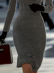 A woman wears a fitted, long-sleeve black and white houndstooth dress with a crew neckline.