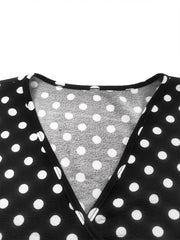 A close-up of the V-neckline on a black and white polka dot dress.