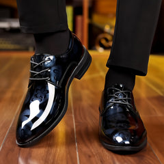 A pair of glossy black lace-up dress shoes with a subtle floral pattern on the upper.