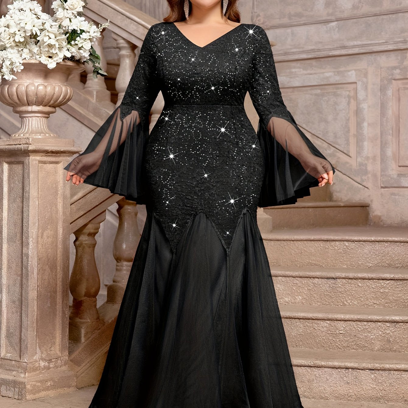 A black plus-size mermaid gown featuring a sequined lace bodice, V-neck, and sheer bell sleeves.