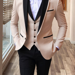 A man wears a beige three-piece suit with a black shawl lapel, vest, and black trousers.