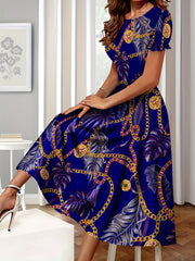 A woman wears a blue A-line dress featuring a golden chain and tropical palm leaf print.