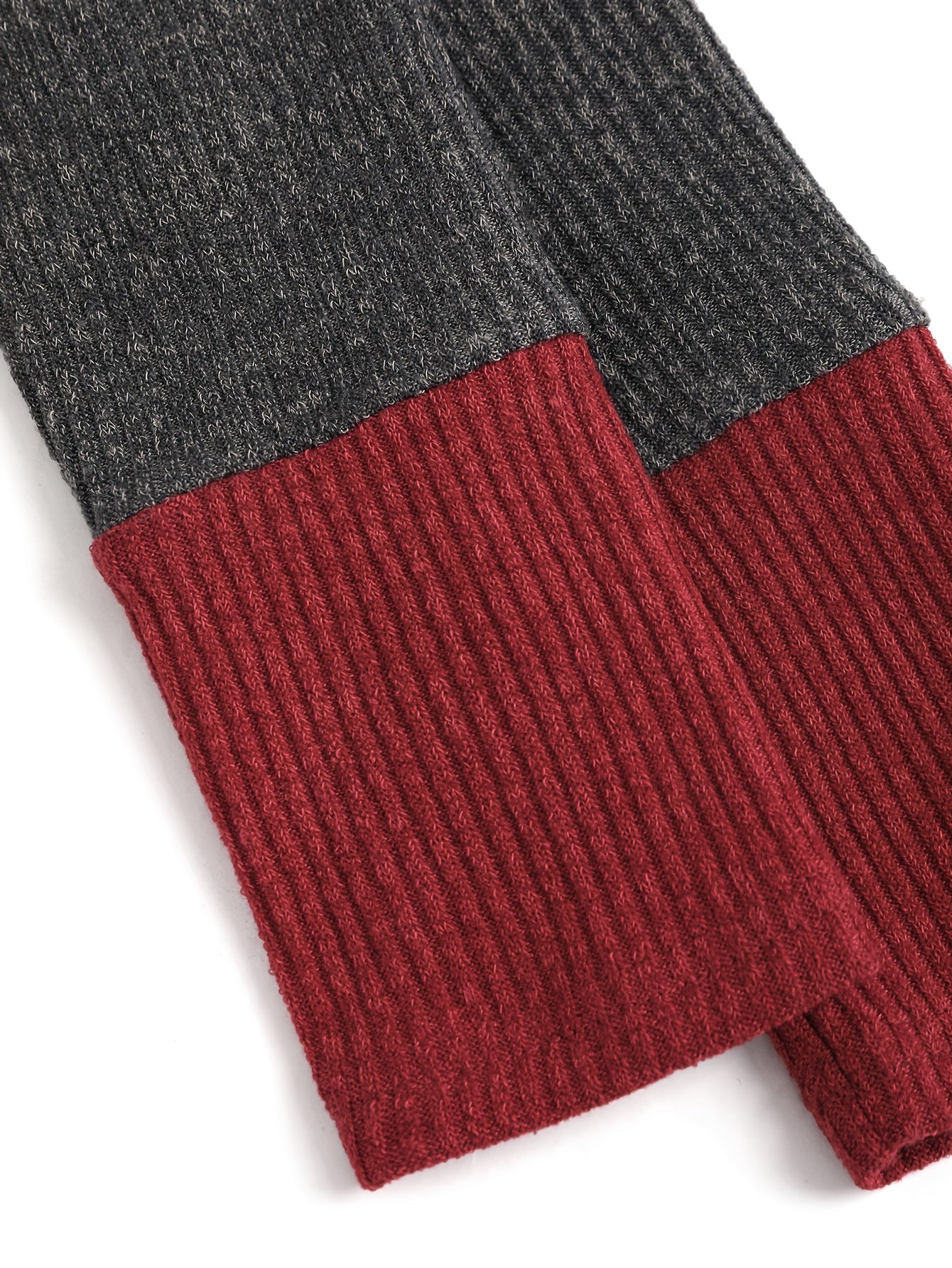 A close-up of a long-sleeved knit cardigan featuring a dark grey upper and a maroon ribbed cuff.